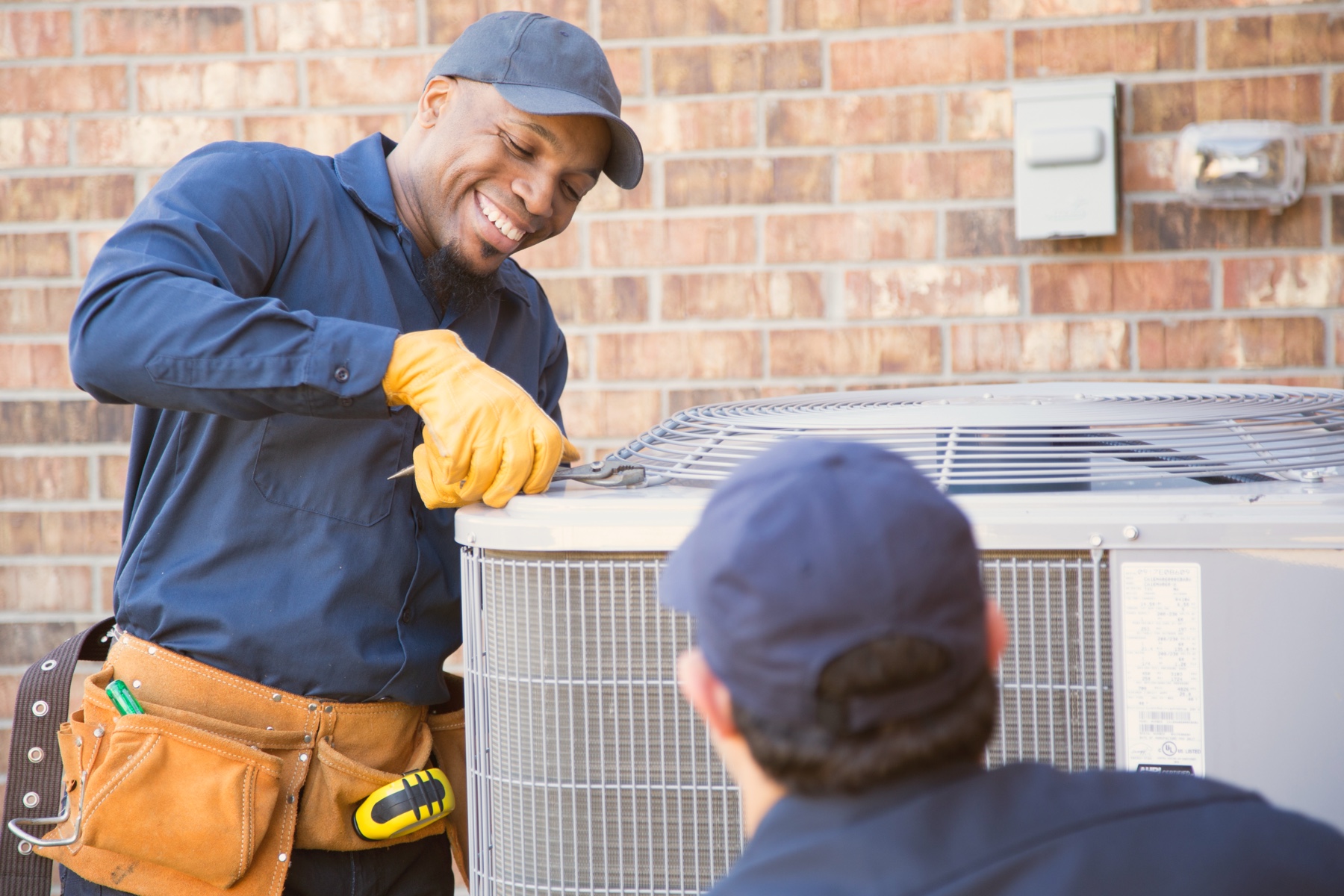 Two technicians working on an exterior cooling unit
